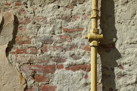 Yellow gas pipe on old brick wall outdoors, space for textの写真素材