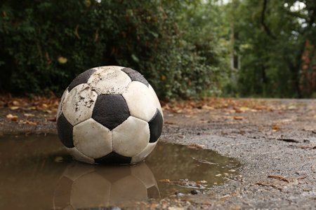 Dirty soccer ball in muddy puddle, space for textの写真素材