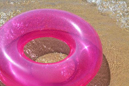 Bright inflatable ring on sandy beach near sea, closeupの写真素材
