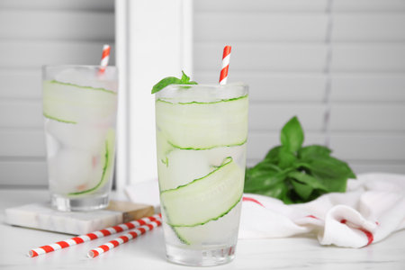 Glasses of refreshing cucumber water with basil on white tableの写真素材