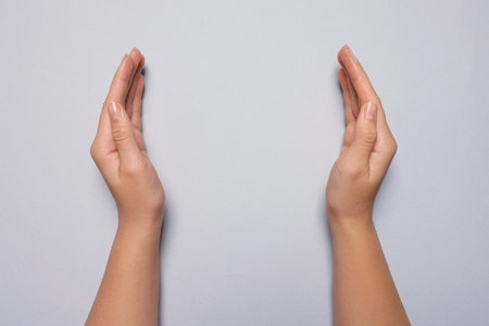 Woman holding on light gray background, closeup of hands. Space for textの写真素材