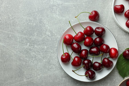 Fresh ripe cherries on light gray table, flat lay. Space for textの写真素材
