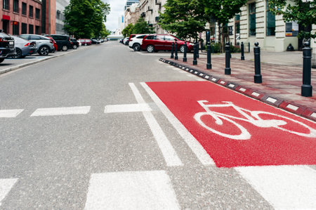 Red bike lane with painted white bicycle sign on city streetの写真素材