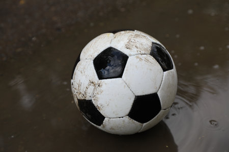 Dirty soccer ball near puddle outdoors, closeupの写真素材