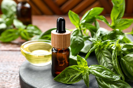 Basil essential oil and fresh leaves on wooden table, closeupの写真素材
