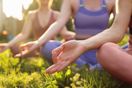 Women meditating on green grass outdoors, closeup. morning yogaの写真素材