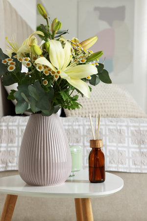Aromatic reed air freshener and vase with bouquet on white table in the bedroomの写真素材