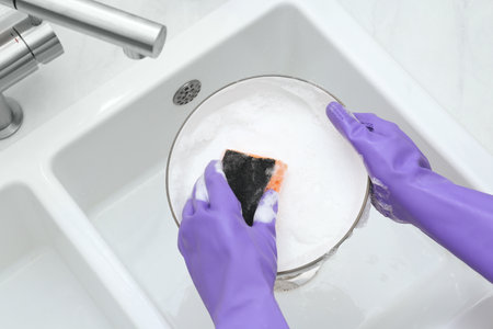 Woman washing plate in kitchen sink, above viewの写真素材