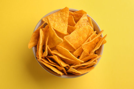 Tortilla chips (nachos) in bowl on yellow background, top viewの写真素材