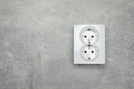 Modern plastic power socket on gray table, top view. Space for text