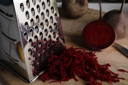 Grater and fresh ripe beetroot on wooden board, closeupの写真素材