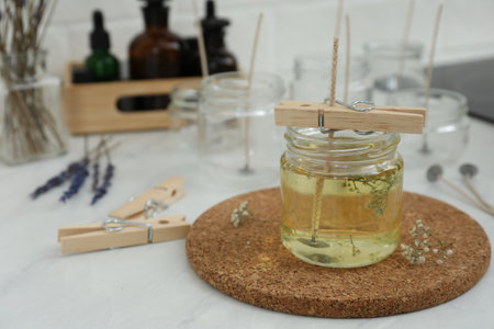 Glass jar with melted wax on white table, space for text. Handmade candle