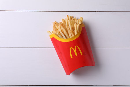 MYKOLAIV, UKRAINE - AUGUST 12, 2021: Big portion of McDonald's French fries on white wooden table,...