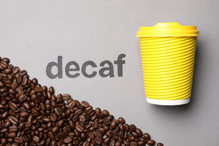 Word Decaf, coffee beans and takeaway paper cup on light gray background, flat layの写真素材