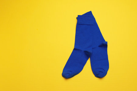 Blue socks on yellow background, flat lay. Space for textの写真素材