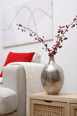 Hawthorn branches with red berries on wooden commode in living roomの写真素材