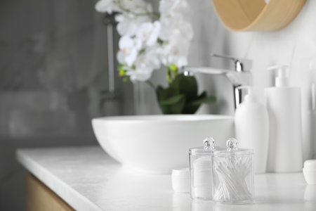 Containers with cotton swabs and pads on white countertop in bathroom. Space for textの写真素材