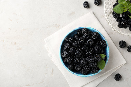 Tasty ripe blackberries and leaves on light table, flat lay. Space for text