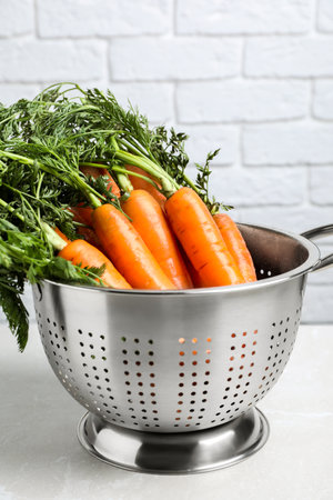Colander with fresh ripe carrots on marble tableの写真素材