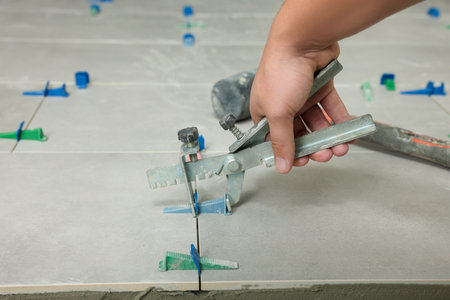 Man installing colorful wedges with plier on tiles, closeupの写真素材