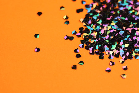 Pile of shiny glitter on orange background, closeup. Space for textの写真素材