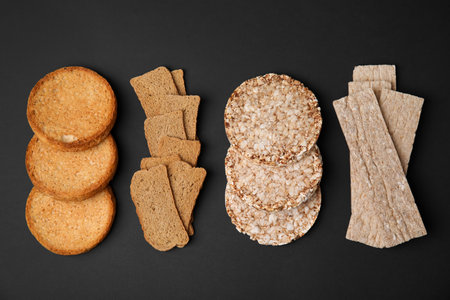 Rye crispbreads, rice cakes and rusks on black background, flat layの写真素材