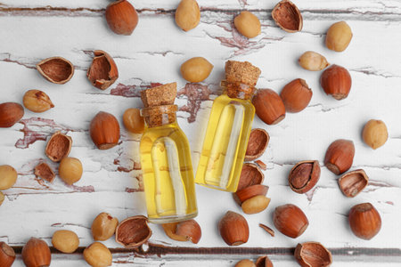 Bottles of hazelnut essential oil and nuts on wooden table, flat layの写真素材