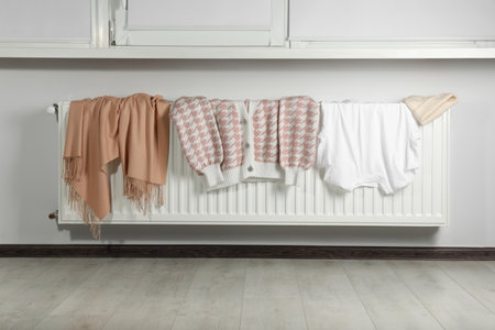Clean clothes on heating radiator near window indoorsの写真素材