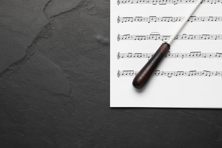 Conductor's baton and sheet music on black background, top view. Space for textの写真素材