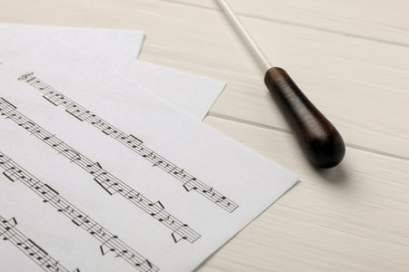 Conductor's baton and sheet music on white wooden tableの写真素材