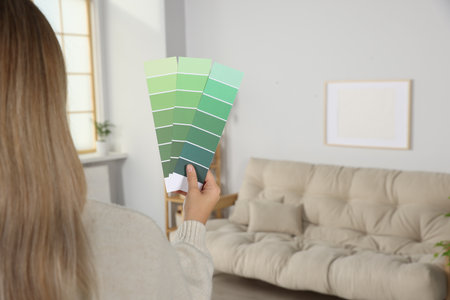 Woman choosing color for wall in room, focus on hand with paint chips. interior designの写真素材