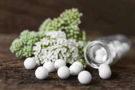 Bottle, homeopathic remedy and flowers on wooden table, closeupの写真素材