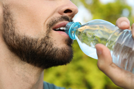 Man drinking water on hot summer day, closeup. Refreshing drinks