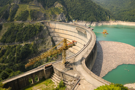 BATUMI, GEORGIA - AUGUST 13, 2022: Tower crane and hydroelectric power station in mountainsの写真素材