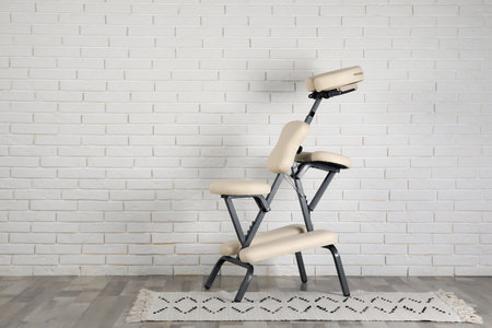 Modern massage chair near white brick wall indoors, space for text. medical equipmentの写真素材