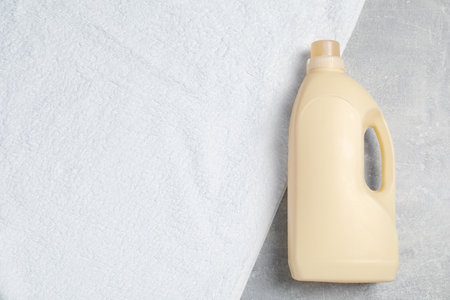 Bottle of laundry detergent and clean towel on light gray table, top view. Space for textの写真素材