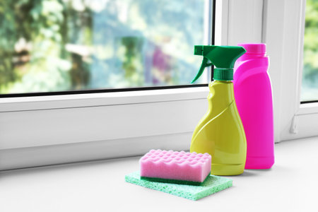 Cleaning supplies and sponges on window sill indoors, space for textの写真素材