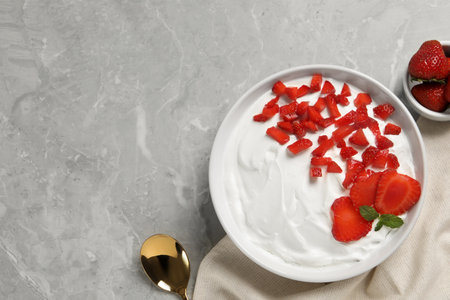 Delicious yogurt with strawberries served on gray marble table, flat lay. Space for textの写真素材