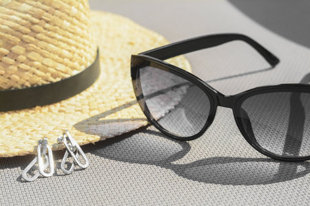 Stylish hat, sunglasses and jewelry on gray surface, closeup