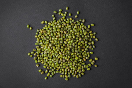 Pile of green mung beans on black background, top view