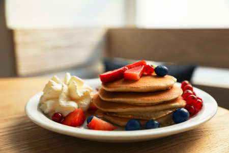 Tasty pancakes with fresh berries and whipped cream on wooden tableの写真素材