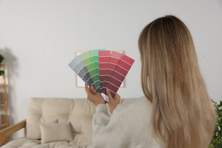 Woman with paint chips choosing color for wall in room. interior designの写真素材