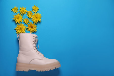 Stylish leather shoe with flowers on light blue background, flat lay. Space for textの写真素材