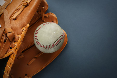 Catcher's mitt and worn baseball ball on dark background, top view. Space for textの写真素材