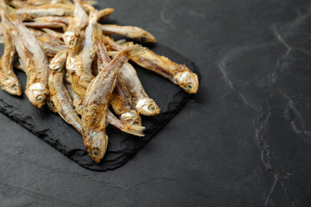 Delicious dried anchovies on black table, closeup. Space for textの写真素材