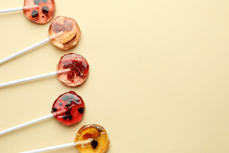 Sweet colorful lollipops with berries on beige background, flat lay. Space for textの写真素材