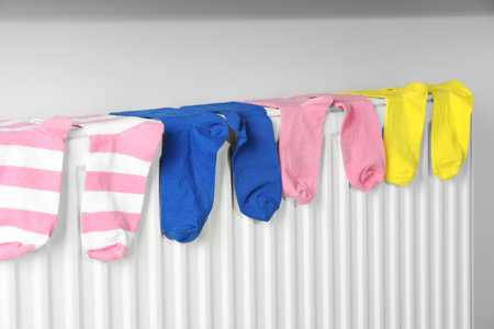 Different colorful socks on heating radiator near white wallの写真素材