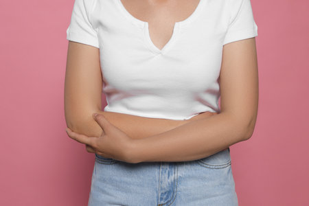 Young woman suffering from menstrual pain on pink background, closeupの写真素材