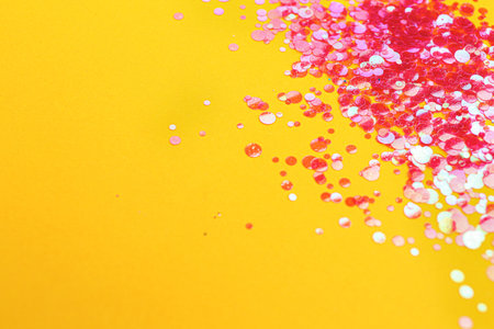 Shiny bright pink glitter on yellow background. Space for textの写真素材