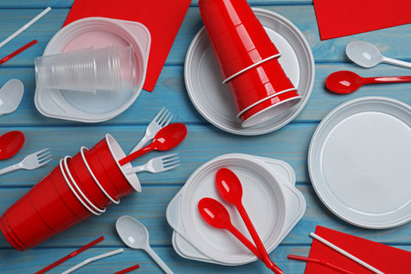 Disposable tableware on light blue wooden background, flat layの写真素材